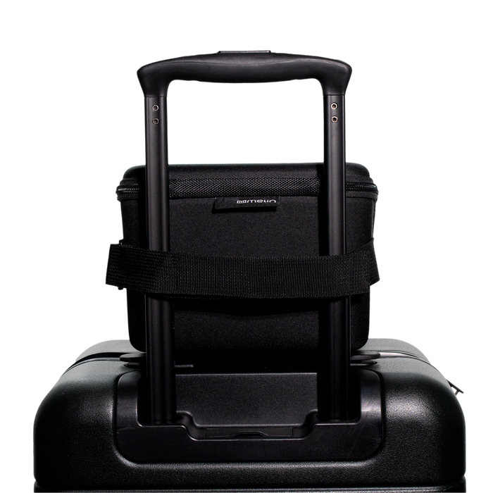 A close up view of the closed Melin 3 Hat Travel case in black attached to a suitcase