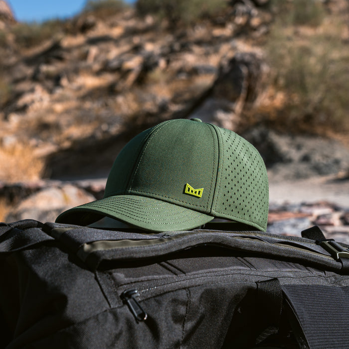 The melin A-Game Icon Hydro in Kombu Green resting on a black backpack in an outdoor setting