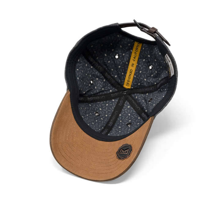 Tan and black baseball cap with adjustable back strap and yellow interior band label.