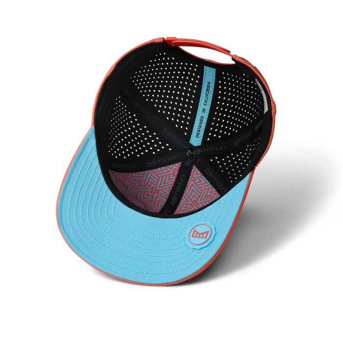 Coral and light blue baseball cap with perforated black interior lining and geometric patterned sweatband.