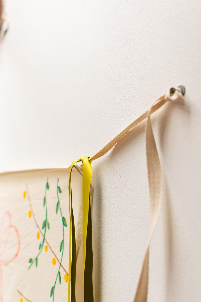 Hand-painted banner hanging on wall with vines, berries and ribbons