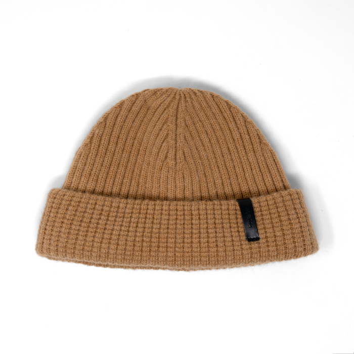 Khaki ribbed knit beanie with a small black label on the cuff.