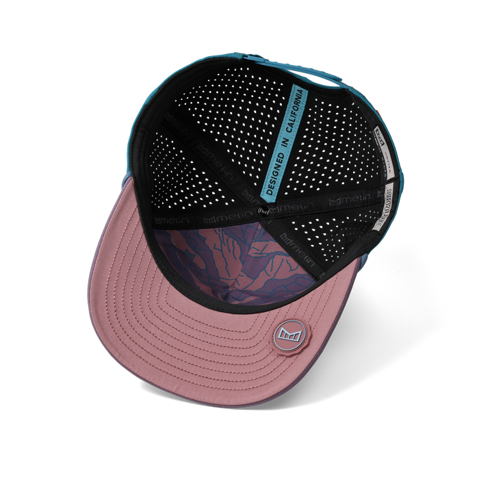 Baseball cap with pink brim, teal back panel, black ventilated interior, and bull icon graphic visible inside crown.
