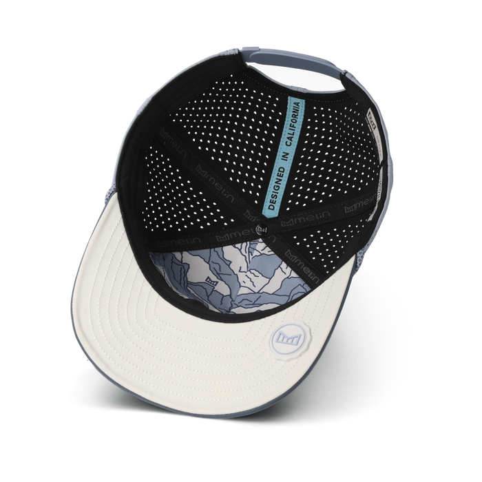 Baseball cap with white front panel, black perforated back, blue trim, and blue patterned interior lining.