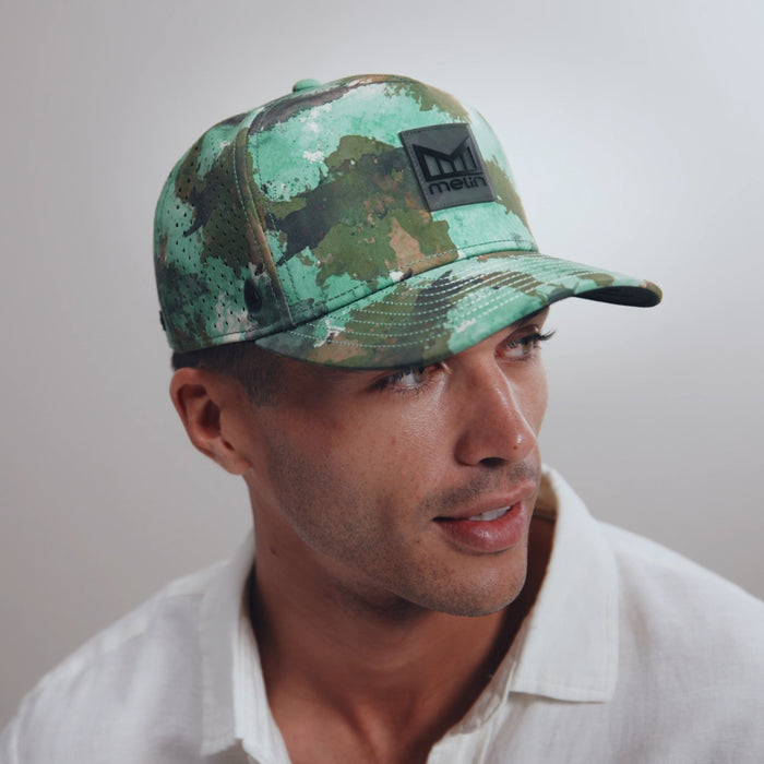 The model-image view of the melin Split Fit Odysea Stacked Hydro hat in watercolor camo