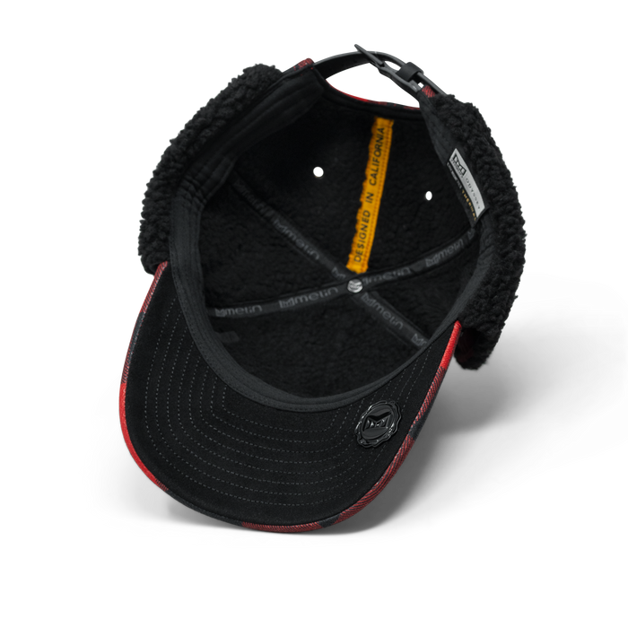Red and black lumberjack thermal cap with fleece lining and adjustable back strap, shown from interior view.