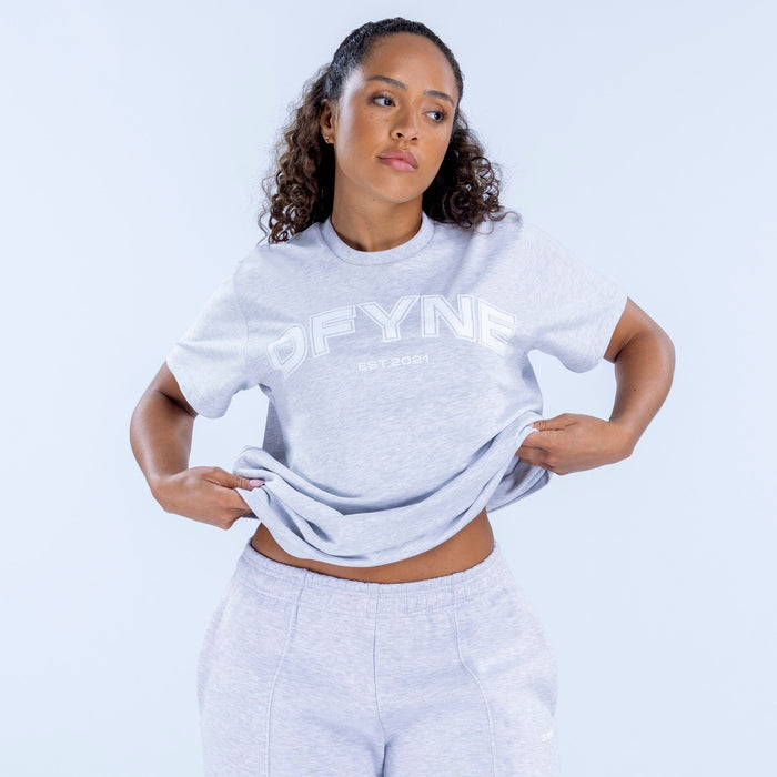 Light gray oversized graphic T-shirt with front logo print, worn at waist