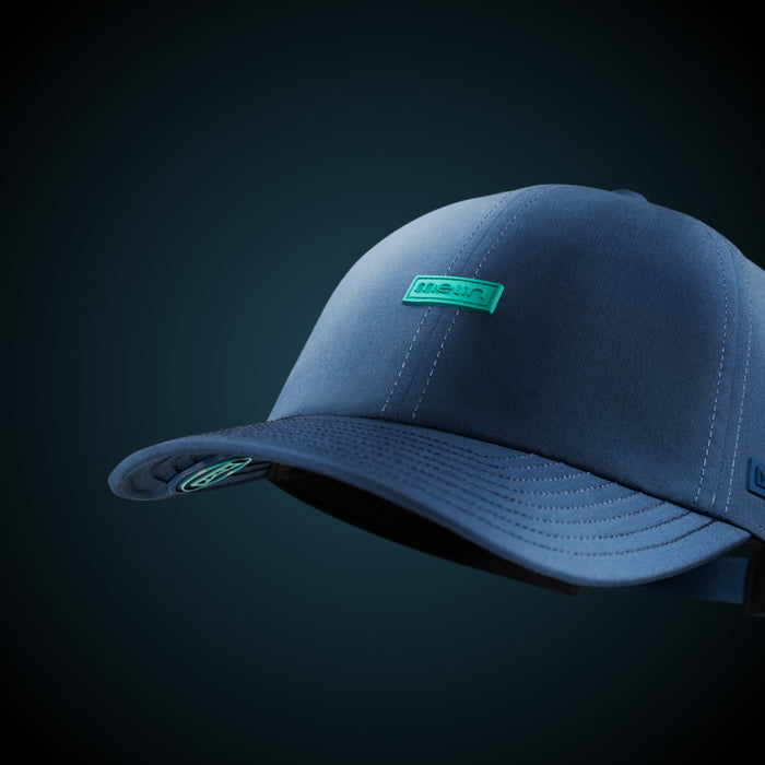 The melin Performance Dad Hat The Legend Hydro in Deep Dive hovering against a blue background