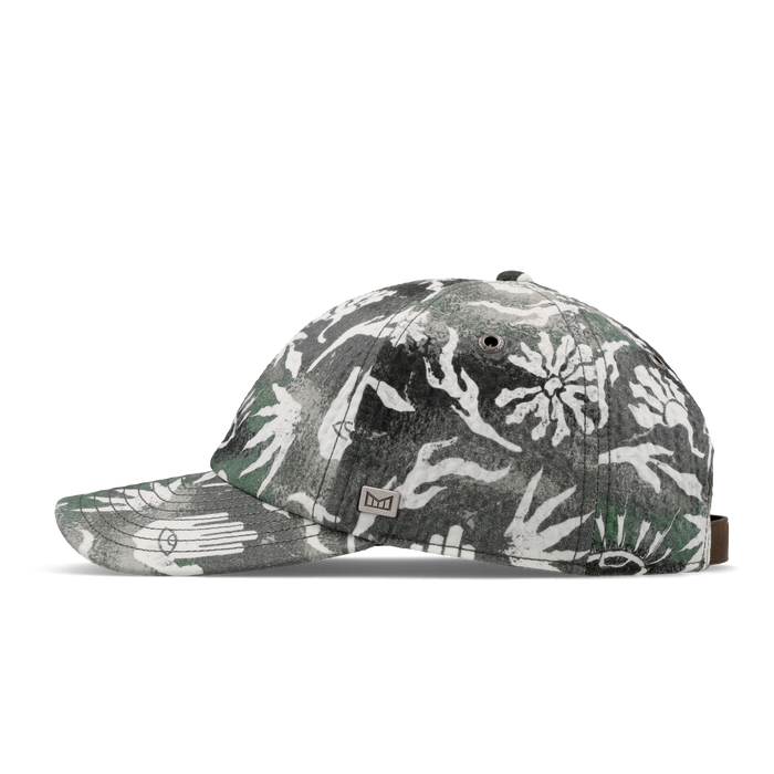 The side view of the melin The Legend Mill Visions Performance Dad Hat in garden