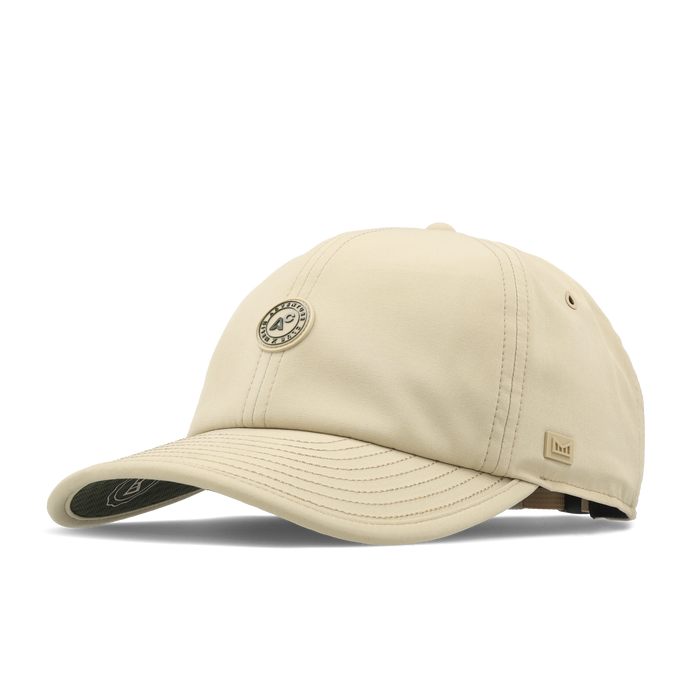The angled view of the melin The Legend Packable Hydro Performance Dad Hat in sand