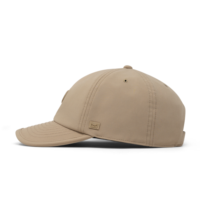 The side view of the melin The Legend Packable Hydro  Performance Dad Hat in  Sand